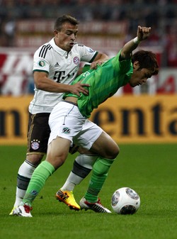 Xherdan Shaqiri berusaha menghentikan serangan yang dilakukan Hiroki Sakai. Reuters/Michaela Rehle.