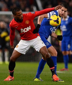 Patrice Evra berebut bola dengan Kevin Mirallas. AFP/Andrew Yates.