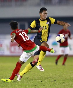 Izzaq Faris Ramlan berusaha melewati Manahati Lestusen dalam pertandingan di Zayyarthiri Stadium, Nay Pyi Taw, Kamis (19/12/2013). Reuters/Soe Zeya Tun.