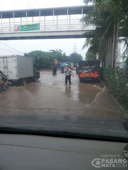 Di Tengah Genangan, Polisi Ini Halau Pemakai Jalan dari Lubang Besar di Daan Mogot