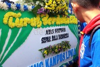 Mereka juga membawa karangan bunga duka cita tanda matinya sepakbola Indonesia.