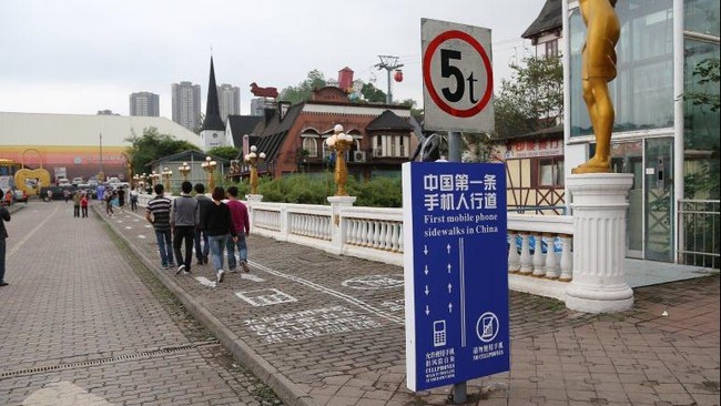 Pejalan kaki di kota Chongqing kini bisa berjalan dengan tenang tanpa perlu khawatir bertabrakan dengan pengguna ponsel setelah ada garis pemisah di trotoar
