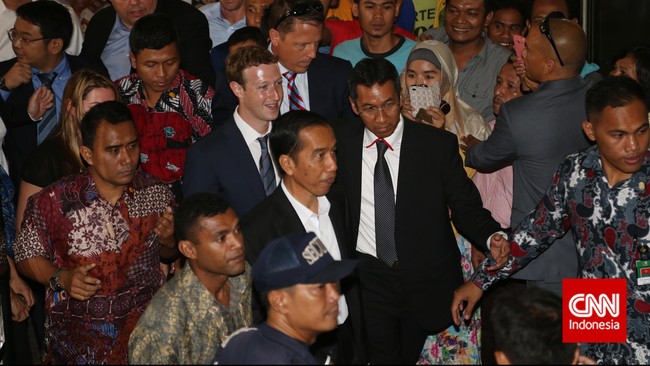 Padanan jas hitam, dasi biru tua dan kemeja putih, Mark akan berpikir ulang jika kemudian hari Jokowi kembali mengajaknya blusukan dengan kostum serupa.