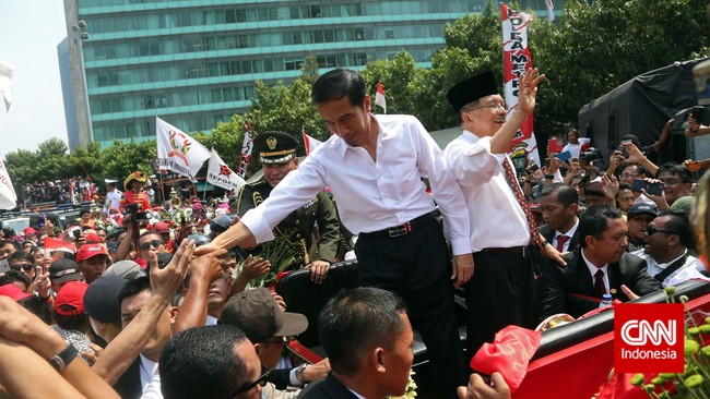 Menyambut kedatangan Presiden Jokowi dan Wakil Presiden Jusuf Kalla, sekelompok massa mengibarkan bendera merah putih raksasa.