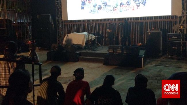 Menonton layar bioskop terbuka sambil menikmati camilan di tengah tanah lapang, pernah menjadi kenangan indah masa 1980-an. Kini, suasana itu dihadirkan lagi.