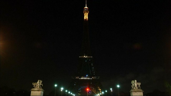 Menara ikon kota Paris itu gelap gulita, sementara puluhan orang menyalakan lilin di kaki Eiffel, berkumpul semalaman mengenang korban penembakan.