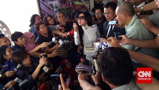 Syahrini datang ke Bareskrim Mabes Polri dengan busana putih dan kaca mata hitam. Ia datang bersama Hotman Paris Hutapea naik mobil mewah Bentley.