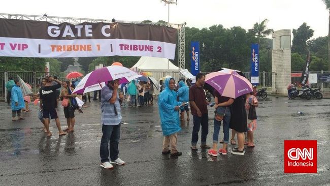 Hujan siang ini tidak menyurutkan langkah para calo tiket konser One Direction. Mereka pakai payung, jas hujan, dan membungkus tiket dengan plastik.