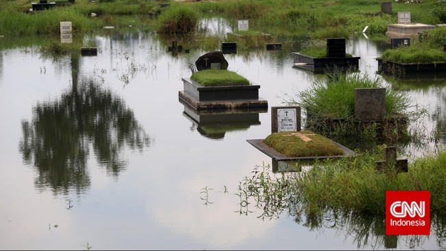 Hujan lebat yang mengguyur Jakarta pada Minggu (7/2) dini hari, membuat sejumlah blok pemakaman di TPU Karet Bivak, banjir.