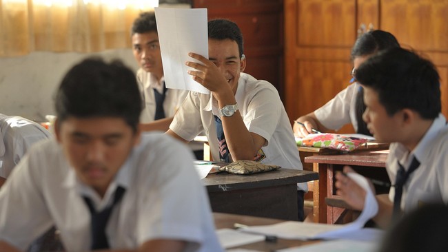 64 Kepsek SMP di Riau Mundur Massal, Resah Diusik Dana BOS Dua siswa berbincang dengan rekannya saat berlangsungnya Ujian Nasional (UN) tingkat SMP/Mts di SMP 9 Denpasar, Bali, Senin (4/5). UN tingkat SMP/MTs 2014/2015 di Bali yang diikuti 65.526 siswa SMP/Mts, 887 siswa Paket B dan 45 siswa SMP LB, dilaksanakan dengan aturan yang sangat ketat untuk menghindari kecurangan. ANTARA FOTO/Nyoman Budhiana/Rei/nz/15.