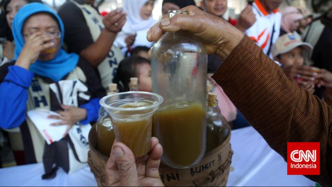 Ibu jamu gendong menuangkan jamu temulawak  gratis kepada pengunjung di kawasan Sarinah, Jakarta, Minggu, 10 Mei 2015. Pada peringatan Hari Konsumen Nasional, masyarakat diajak minum gratis berbagai jamu tradisional sekaligus mengajak melestarikan jamu sebagai minuman kesehatan tradisional khas Indonesia. CNN Indonesia/Safir Makki