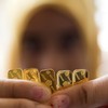 Tangan petugas menunjukan deretan logam mulia di Jakarta, Kamis (21/5). Harga jual dan beli kembali (buyback) emas PT Aneka Tambang Tbk (Antam) pada perdagangan hari ini masih stagnan, dengan harga jual emas di Rp557.000/gram dan harga buyback emas p