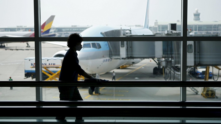 An employee wearing a mask to prevent contracting Middle East Respiratory Syndrome (MERS) wipes a travelator at Incheon International Airport in Incheon, South Korea, June 14, 2015. A South Korean hospital suspended most services on Sunday after being identified as the epicentre of the spread of the deadly respiratory disease that has killed 15 people since being diagnosed in the country nearly four weeks ago.   REUTERS/Kim Hong-Ji