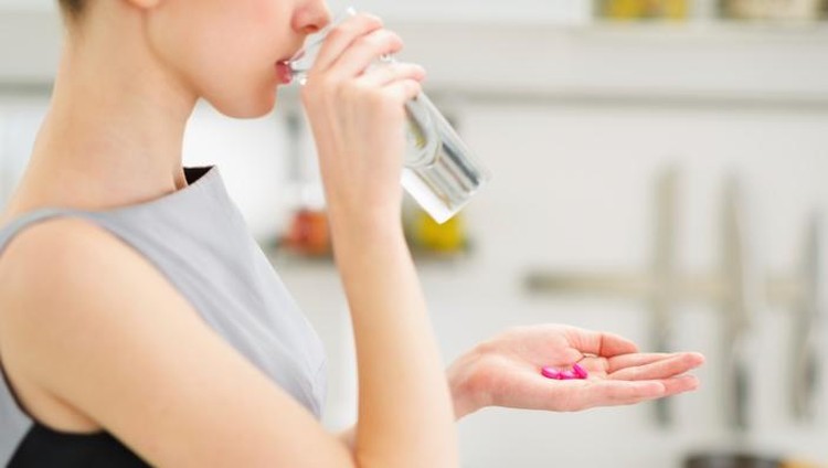 Ilustrasi seorang wanita yang sedang mengonsumsi vitamin atau suplemen