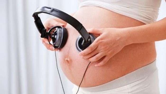 seorang ibu sedang memperdengarkan musik kepada janin dalam kandungannya