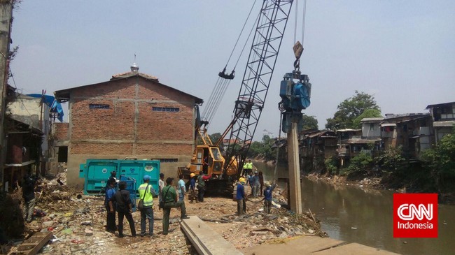 Musala yang masih berdiri terletak di RW03 menghalangi akses alat berat yang akan digunakan untuk memasang tiang pancang untuk menurap Kali Ciliwung.