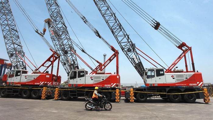 Pekerja pelabuhan melintas di depan  mobil 