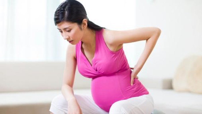Tired young pregnant woman sitting on fitness ball