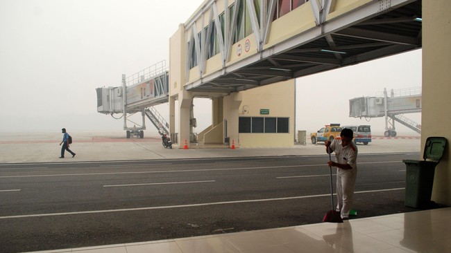 Petugas membersihkan area landasan pacu yang tidak beroperasi karena diselimuti kabut asap di Bandara Sultan Syarif Kasim II, di Pekanbaru, Riau, Senin (14/9). Kabut asap kebakaran hutan dan lahan yang menyelimuti landasan pacu bandara mengakibatkan 12 penerbangan menuju dan dari Pekanbaru dibatalkan. ANTARA FOTO/Rony Muharrman/kye/15