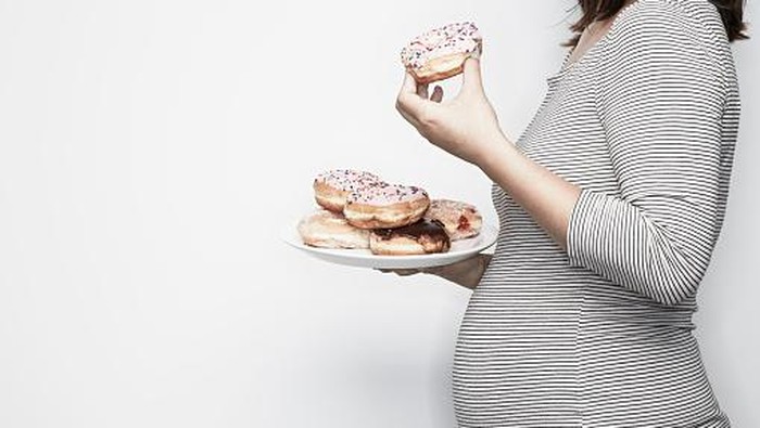 Pregnant woman holding plate of doughnuts