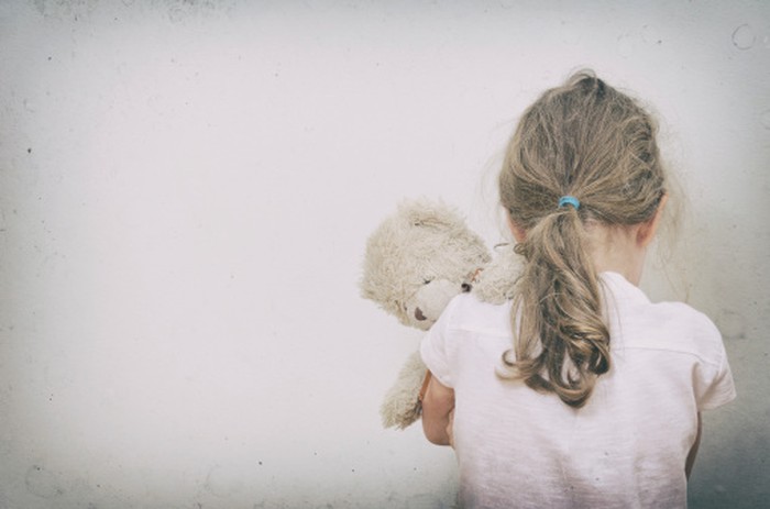 Anak perempuan menangis dengan menghadap tembok sambil memeluk bonekanya. Anak perempuan menangis dengan menghadap tembok sambil memeluk bonekanya.