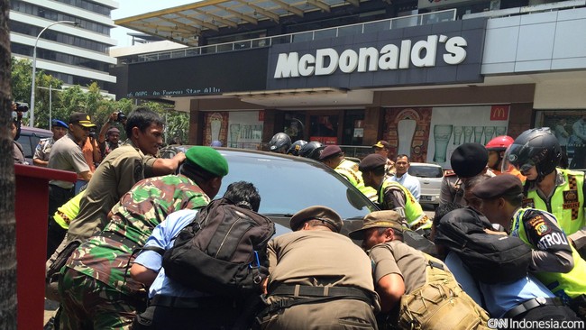 Beberapa kendaraan terlihat masih terparkir di area depan gedung. Polisi, petugas pemadam dan warga tampak mengangkat kendaraan-kendaraan tersebut.