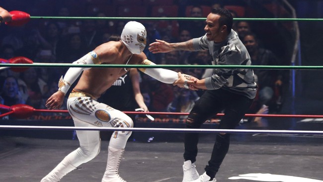 Lewis Hamilton memainkan fusbol di atas ring gulat Arena Mexico dengan pegulat bertopeng, Mistico. Setelah itu Hamilton melakukan simulasi gulat dengan Mistico.