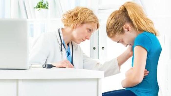 Early Teenage Girl with stomachache at doctors office.