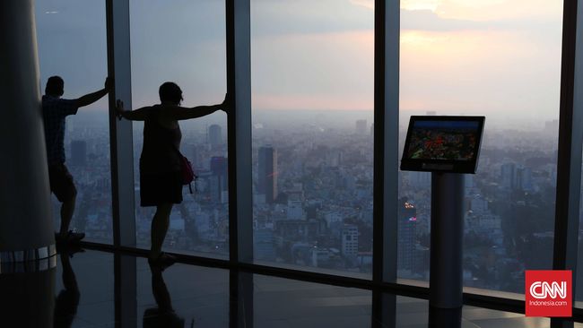 Dua turis berdiri di depan kaca memandang kota Ho Chi Minh dari Saigon Skydeck Bitexco Financial Tower. Saigon Skydeck terletak di lantai 49 merupakan lokasi wisata baru untuk memandang pemandangan kota Ho Chi Minh 360 derajat. CNN Indonesia/Safir Mak