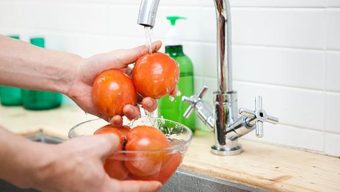 a person washing tomatoes in the kitchen