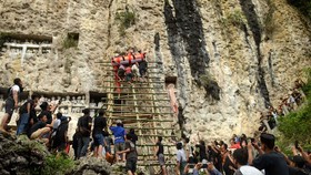 Sejumlah anggota keluarga mengangkat jenazah ke liang kuburan batu di Pekuburan Batu Suaya, Sangalla, Tana Toraja, Sulawesi Selatan, Sabtu (2/1). Prosesi mangea atau penguburan jenazah di tebing gunung batu merupakan tahap terakhir dari upacara adat