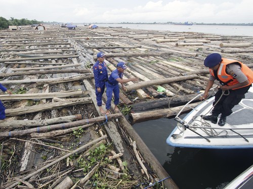 Petugas Satpolair Polda Kalsel memeriksa ratusan batang kayu yang diamankan di desa Ujung Panti Banjarmasin, Senin (29/2). Kayu log sebanyak 400 batang atau 3500 meter kubik tersebut dihanyutkan dari Muara Teweh Kalimantan Tengah tanpa disertai surat
