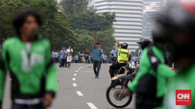 Pengemudi pengujuk rasa di Gedung DPR mendekati rombongan pengemudi Gojek di Slipi sambil membawa kayu dan batu namun bisa dicegah polisi. 
