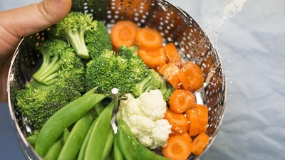 Piring sayur kukus segar berisi brokoli, wortel, dan buncis, disajikan dengan saus kacang