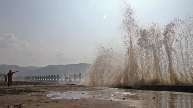 Wisatawan menikmati pemandangan gelombang air pasang yang menghempas pagar pembatas Pantai Sine, Tulungagung, Jawa Timur, Senin (6/6). Fenomena gelombang air pasang selama beberapa pekan terakhir selain berdampak merusak di kawasan pesisir juga menjadi fenomena yang diminati wisatawan. ANTARA FOTO/Destyan Sujarwoko/foc/16.