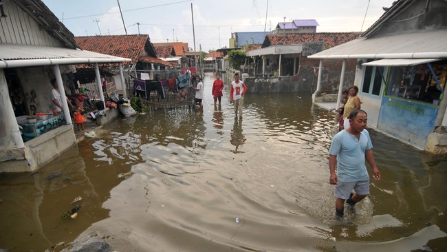 Sejumlah warga melintasi banjir rob di Muarareja, Tegal, Jawa Tengah, Kamis (9/6). Ratusan rumah warga terutama kampung nelayan di daerah pantai utara terendam banjir rob mencapai tinggi 30 sentimeter sehingga mengganggu aktivitas warga. ANTARA FOTO/Oky Lukmansyah/foc/16.