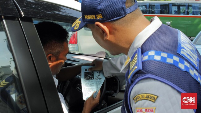 Petugas Dinas Perhubungan (Dishub) memberikan flyer kepada supir yang ditegur oleh petugas polisi saat berlangsungnya ujicoba sistem pelat ganjil-genap di kawasan Sudirman, Jakarta Pusat pada Rabu, 27 Juli 2016. Uji coba sistem pelat ganjil-genap dilakukan oleh Dinas Perhubungan (Dishub) dan Polda Metro Jaya untuk mengatasi angka kemacetan di Jakarta. CNN Indonesia/Gautama Padmacinta.