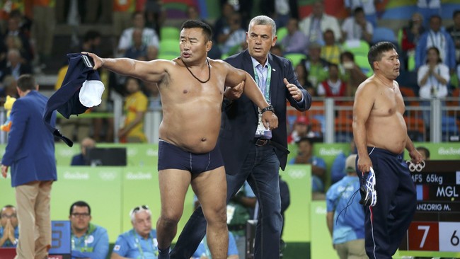Dua pelatih gulat tim Mongolia, Byambarenchin Bayaraa dan Tsenrenbataar Tsostbayar, melucuti baju dan celana mereka dan melemparnya ke matras.