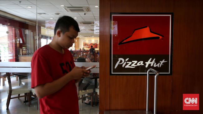 Pengunjung melintasi restaurant cepat saji Pizza Hut di Jakarta, Minggu, 4 September 2016. CNN Indonesia/Safir Makki