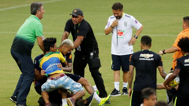Penyerang Brasil, Neymar Junior, tak berdaya ketika 'disergap' dua penyusup lapangan ketika Selecao sesi latihan di Stadion Manaus, Amazon.