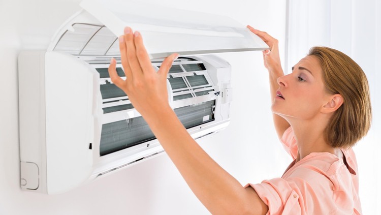 Young Beautiful Woman Opening Air Conditioner At Home
