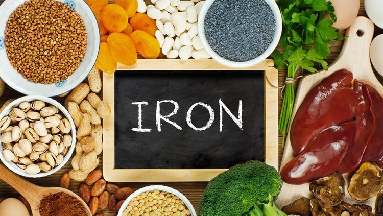 zat besi Collection iron rich foods as liver, buckwheat, eggs, parsley leaves, dried apricots, cocoa, lentil, bean, blue poppy seed, broccoli, dried mushrooms, peanuts and pistachios on wooden table.