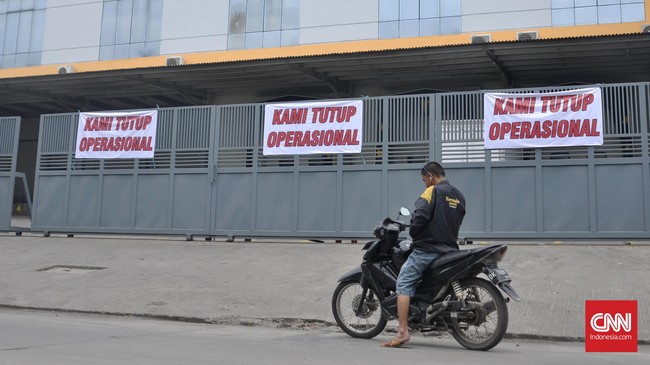 Warga melintas di depan pabrik yang tutup operasional di Muara Baru, Jakarta, Senin, 10 Oktober 2016. Perusahaan Umum Perikanan Indonesia (PerumPerindo) menaikkan tarif sewa lahan dari Rp 236 Juta per hektar per tahun menjadi Rp 1,5 miliar per hektar per tahun. CNN Indonesia/Djoent Sugiarto