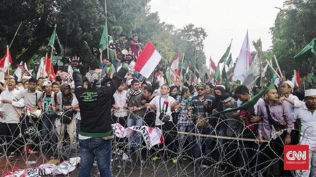 Pedemo berhadapan langsung dengan polisi yang dibatasi pagar kawat. Teriakan massa menutupi imbauan polisi yang ingin menenangkan massa.