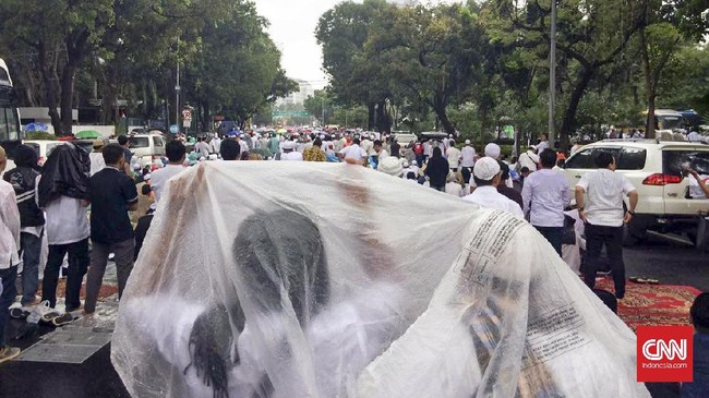Di tengah-tengah ibadah salat Jumat, hujan disertai angin kencang mulai turun. Namun, massa berkeras tak meninggalkan tempat.