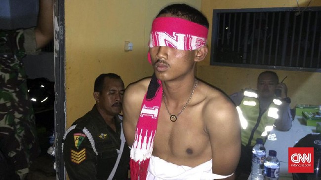 Seorang penonton melempar batu ke arah kerumunan penonton yang masih mengantre masuk ke dalam Stadion Pakansari. Ia pun ditangkap