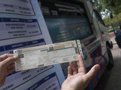 Warga menunjukkan STNK yang baru diperpanjang di Samsat Keliling, Jakarta, Selasa (3/1). Pemerintah melalui Kepolisian Republik Indonesia akan menerapkan tarif baru penerbitan dan pengurusan Surat Tanda Nomor Kendaraan (STNK) dan Buku Pemilik Kendara
