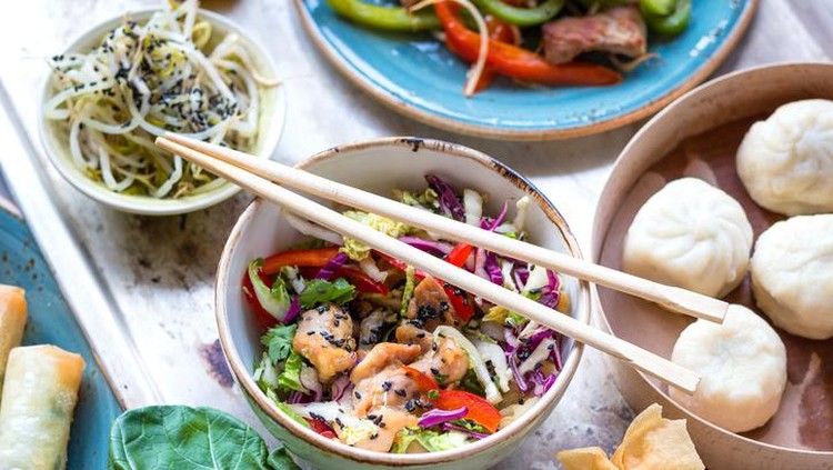 Asian salad with chicken stir-fry, bok choy, cabbage and pepper, dim sum bowl, spring rolls, seaweed and beef salad with vegetables. Chinese style dinner. From above. Pan-asian food. Selective focus