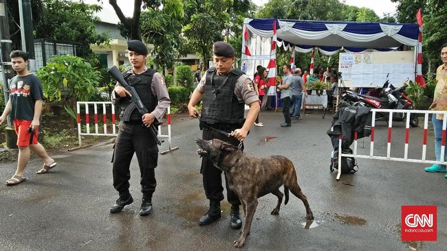 Petugas mengerahkan personel bersenjata laras panjang dan anjing pelacak di TPS tempat Sylviana Murni memilih di kawasan Duren Tiga, Jakarta Timur.