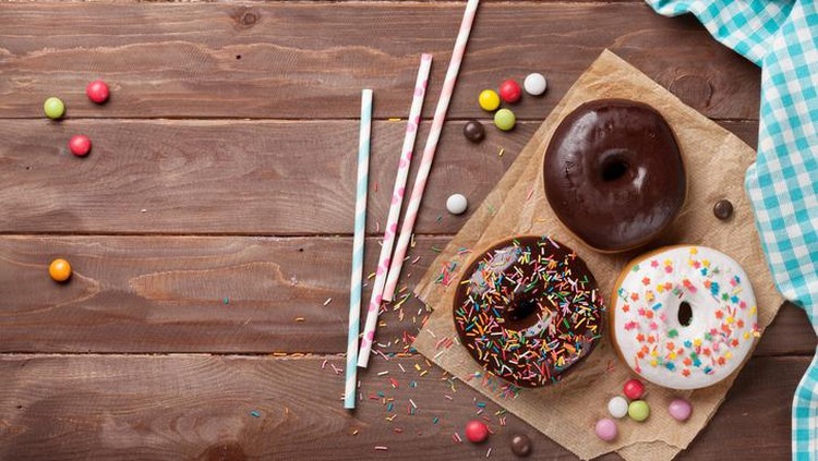Donuts and candies on wooden table. Top view with copy space